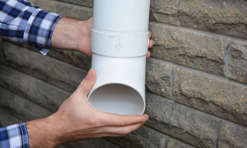 Hands holding part of downpipe